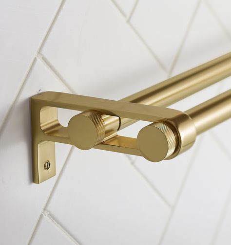 a close up of a metal handle on a white tile wall with gold colored handles