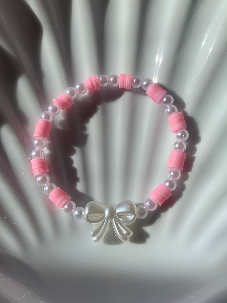 a pink and white bracelet with a bow on it