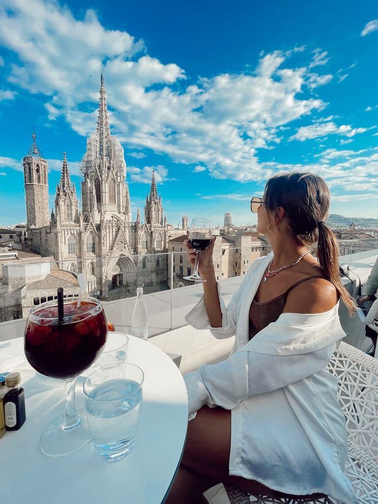 a woman sitting at an outdoor table with a glass of wine in front of her