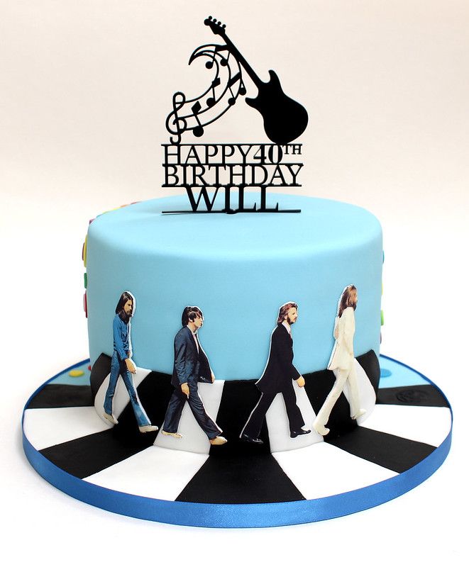 a birthday cake with the beatles on it and an inscription happy birthday will written in black