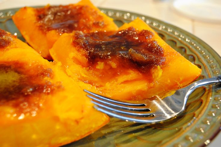 two pieces of pineapple dessert on a plate with a fork and glass bowl in the background