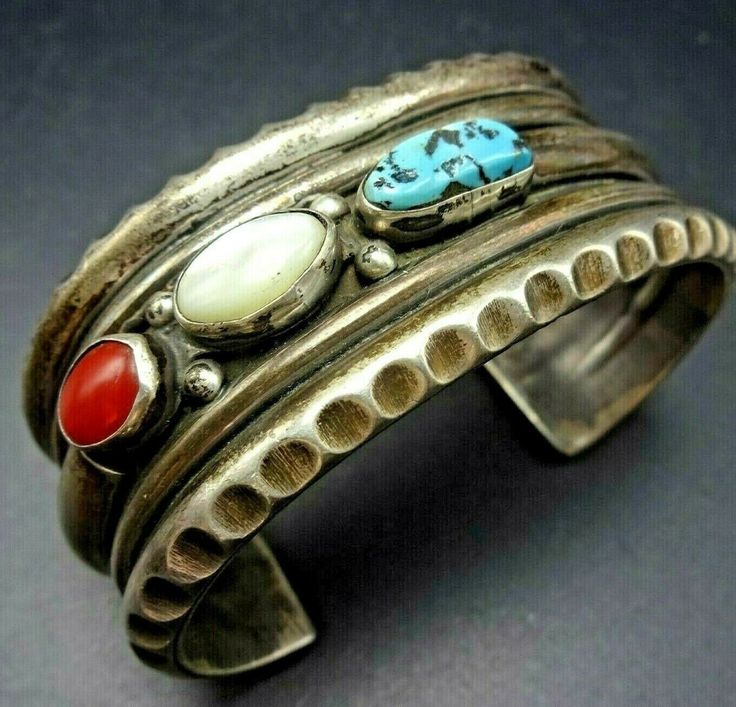 "VINTAGE NAVAJO BRACELET DESCRIPTION: This amazing cuff features cabs of old red Mediterranean coral, natural Kingman turquoise, and mother of pearl. The gemstones are secure in smooth bezel, on a foundation of heavy gauge, chisel stamped ingot silver. This bracelet will be a cherished addition to your collection of fine vintage Native American jewelry. MEASUREMENTS: Interior of the cuff measures 5 3/8\" with an additional 1 1/2\" non-adjustable gap. Total circumference: 6 7/8\" Measures 2 5/8\" Vintage Cuff Bracelet With Natural Stones Gift, Vintage Cuff Bracelet With Natural Stones, Vintage Bangle Cuff Bracelet With Natural Stones, Vintage Natural Stones Cuff Bracelet, Vintage Natural Stones Cuff Bangle, Vintage Gemstone Cuff Bracelet Collectible, Vintage Red Gemstone Bracelets, Silversmith Jewellery, Bones Bracelet