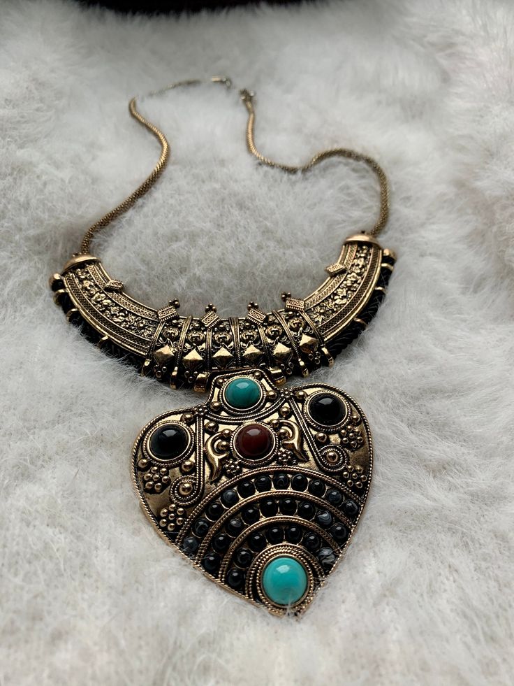 You will absolutely adore this piece!   Purchased in Spain, at a fantastic little shop, in a town that still has stone streets, a moat, and a castle. She's dramatic and fantastic.  It is a large, chunky, heavy statement piece.   Aged gold with turquoise and neutral colored stones.   Perfect for simple sweaters & dresses, or costumes. Bohemian Heart-shaped Metal Necklaces, Unique Antique Gold Metal Necklace, Heavy Brass Necklaces For Gifts, Bohemian Gold Jewelry With Large Stone, Unique Antique Gold Festival Jewelry, Antique Gold Unique Festival Jewelry, Gold Bohemian Jewelry With Large Stone, Unique Antique Gold Jewelry For Festival, Heavy Brass Necklace For Gift