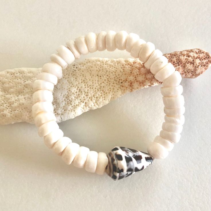 "Natural white Hawaiian puka shell and Hebrew cone shell stretch bracelet. Genuine white smooth polished 8mm puka shell stretch bracelet accented with authentic Hawaiian Hebrew cone shell. Lovely puka shells are found throughout the Islands of the Pacific. Hawaiian Hebrew cone shell with it characteristic brown and white pattern is found on Hawaii's North Shores. Pukas are natural with normal imperfections from the pounding surf. Stretch bracelet is made to order. Please add 3/4\" to 1\" to actu Adjustable White Coastal Beaded Bracelets, Adjustable White Coastal Style Bracelets, Adjustable White Stretch Bracelet With Beachy Style, White Adjustable Stretch Bracelet With Beachy Style, White Coastal Beaded Bracelets For Vacation, White Coastal Beaded Bracelets For Beach, White Coastal Style Bracelet For Gift, White Adjustable Beachy Stretch Bracelet, White Shell Bracelet For Vacation