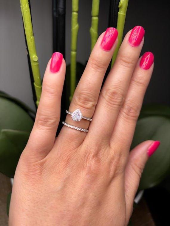 a woman's hand with pink nail polish and a diamond ring on her finger