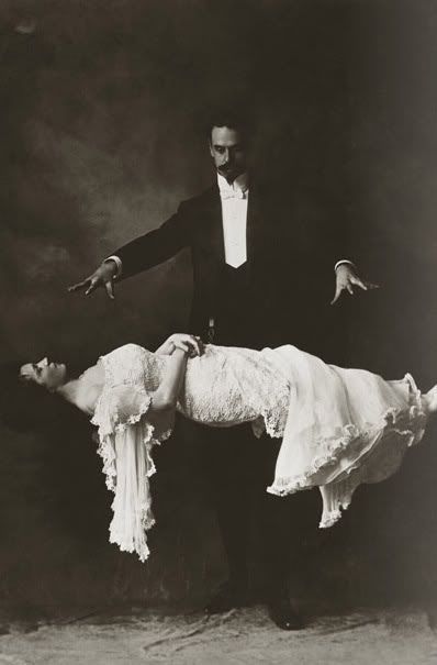 a man in a tuxedo is holding the back of a woman