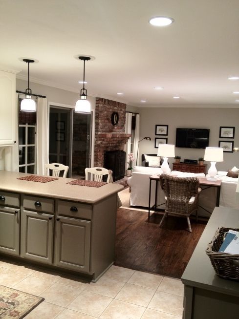 a large open concept kitchen and living room with wood floors, white walls, gray cabinetry, and fireplace