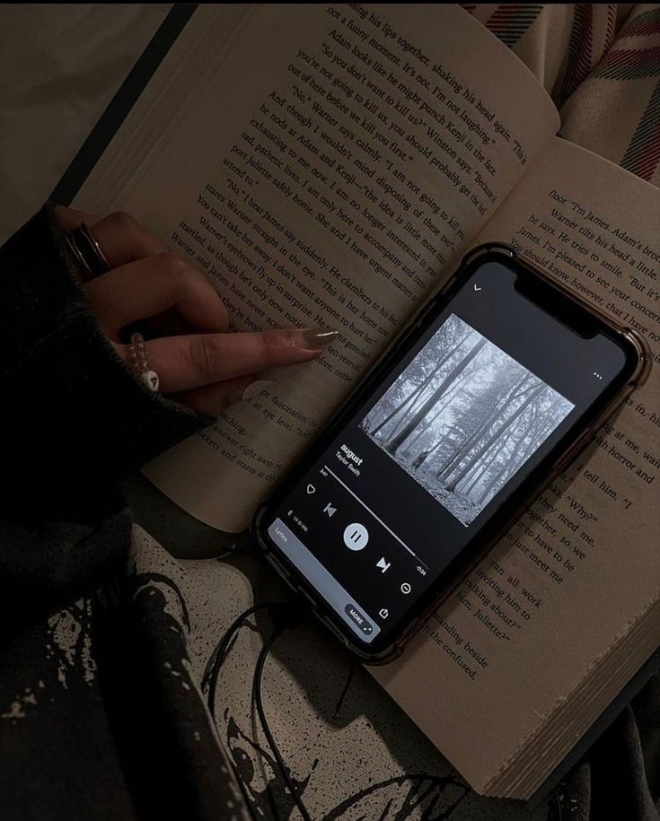 an open book sitting on top of a table next to a cell phone