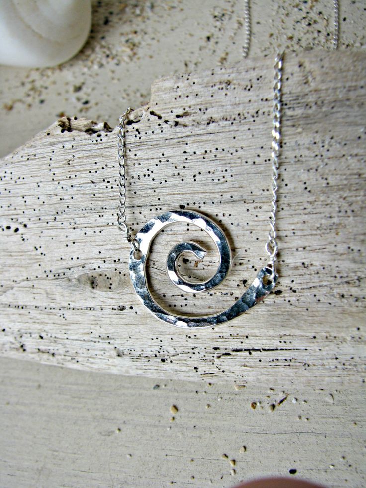 "A tiny Koru necklace made of hand-formed and hand-hammered Sterling Silver ($45-Shown) or 14k Gold-Filled ($55). The Koru is my very favorite symbol. I love it for it's graceful shape (that also resembles a wave), but I love it even more for its symbolism. The Koru (pronounced Koh-Doo) is based on the Maori Koru Fern, as it opens up and unfurls. It represents \"New Life\" or \"New Beginning\". It also stands for \"Circle of Life\" or \"Eternity\", making it a perfect gift between family or frie Modern Twist Swirl Jewelry As Gift, Modern Twist Swirl Jewelry For Gift, Spiral Hammered Jewelry As Gift, Spiral Hammered Jewelry Gift, Modern Twist Hammered Jewelry As Gift, Sterling Silver Swirl Jewelry As A Gift, Hammered Jewelry With A Modern Twist As A Gift, Hand Forged Silver Spiral Necklace, Hammered Modern Twist Jewelry For Gifts