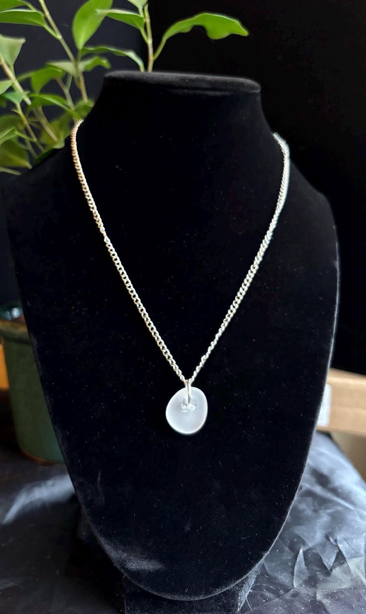 Discover the timeless allure of our frosted white pendant necklace, a unique piece of wearable art that embodies the beauty and tranquility of Lake Michigan. This exquisite pendant features genuine sea glass, meticulously handpicked from the shores of Lake Michigan and expertly handcrafted into a one-of-a-kind accessory. Specifications: -Pendant length:  around 1 inches -Amount of sea glass: 1 piece -Chain Length: 16" stainless steel nickel free chain adjustable -Clasp:lobster claw  adjustable -Materials: Genuine Lake Michigan sourced Sea Glass,stainless steel nickel-free metal chain, wire Features: -Authentic Lake Michigan Sea Glass: Carefully handpicked from the pristine shores of Lake Michigan, ensuring a one-of-a-kind piece that is never reshaped. When picking pairs we look for similar White Jewelry With Adjustable Glass Chain, Round Sea Glass Jewelry Gift, Minimalist Silver Glass Necklaces, White Minimalist Glass Jewelry, Minimalist Handmade Necklace With Recycled Glass, Minimalist Handmade Necklaces With Recycled Glass, Handmade Minimalist Clear Necklace, Sea Glass Round Necklace As Gift, Round Sea Glass Necklace As A Gift