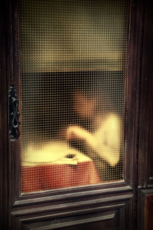 the reflection of a person sitting in front of a window with a cup on it