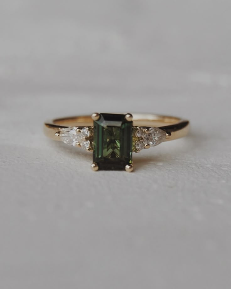 a green and white diamond ring sitting on top of a table