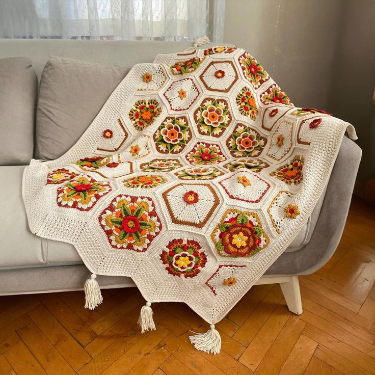 a crocheted granny blanket on a couch in a living room with wood flooring