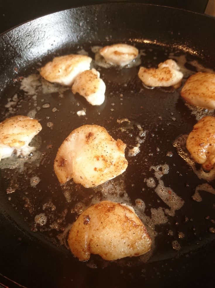 some chicken is cooking in a frying pan on the stove with oil over it