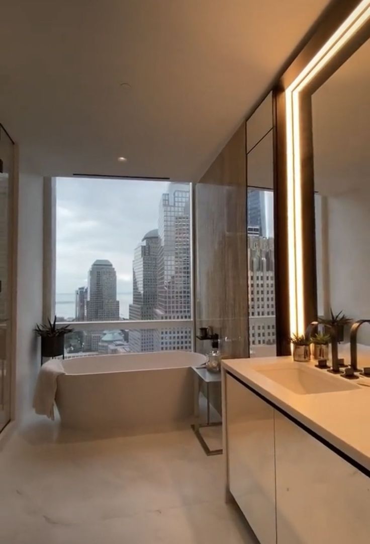 a bathroom with a tub, sink and large window looking out on the cityscape