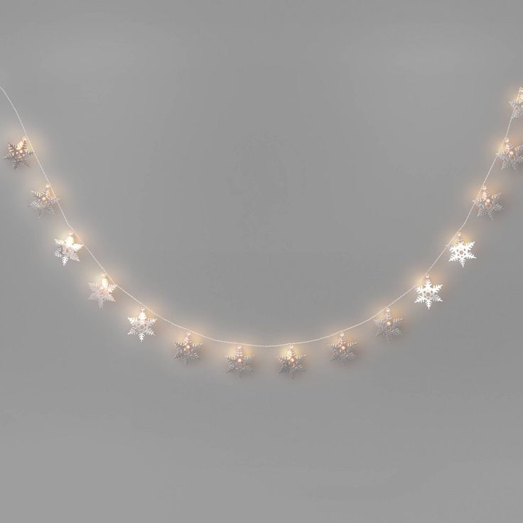 a string of christmas lights with snowflakes hanging from it's sides on a gray background