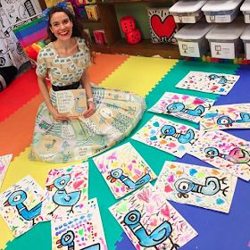 a woman sitting on the floor in front of many cards with numbers and birds painted on them