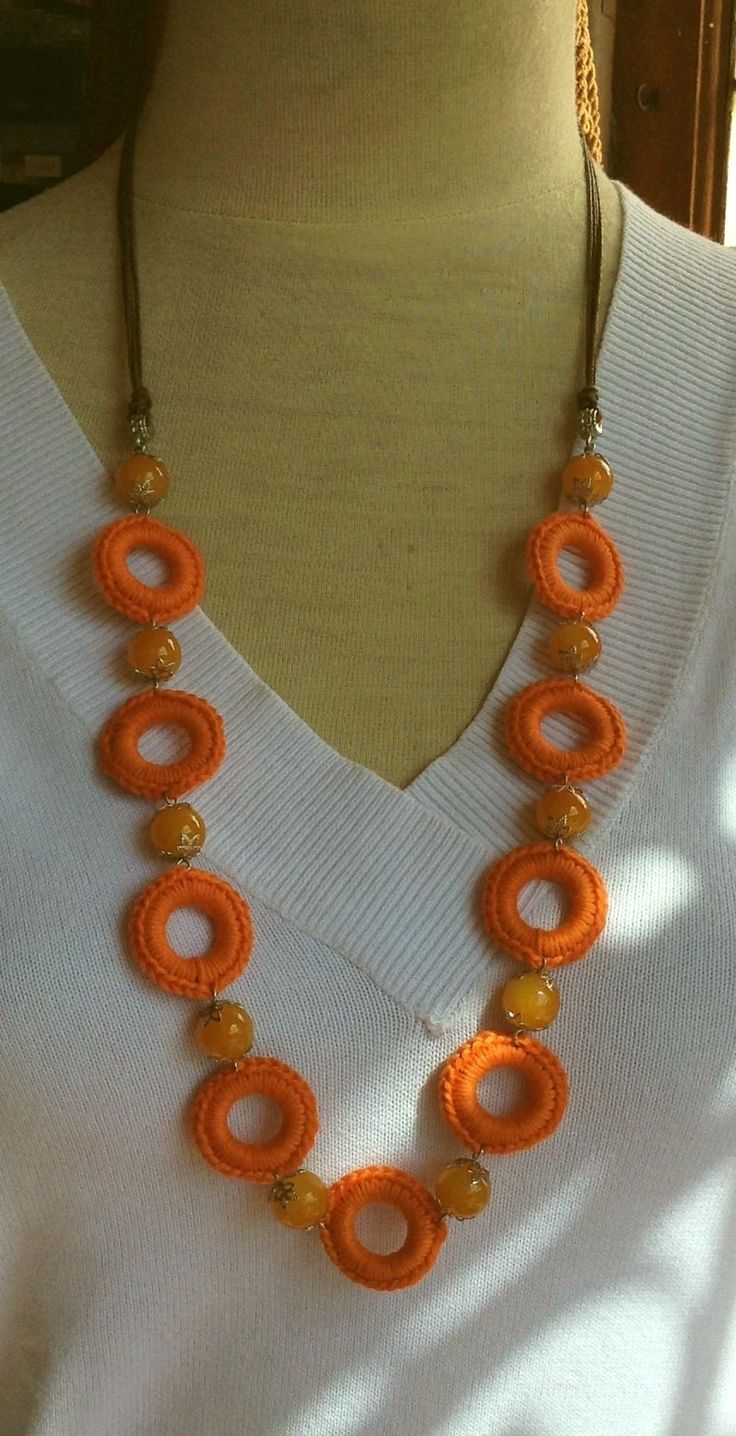 an orange necklace is displayed on a mannequin's neckline in front of a white shirt