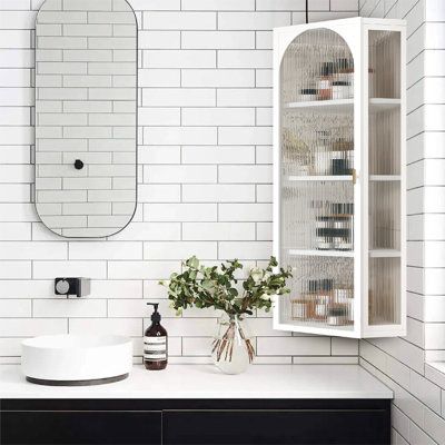 a white bathroom with black and white tile on the walls, sink and mirror above it