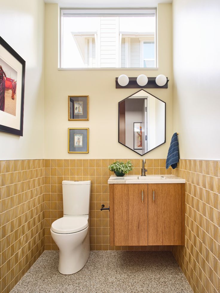 a bathroom with a toilet, sink and pictures on the wall above it's mirror