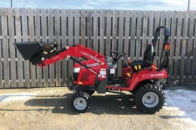 a small red tractor parked in front of a fence