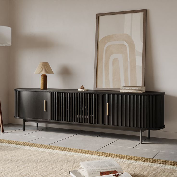 a living room with a book on the floor next to a lamp and a cabinet