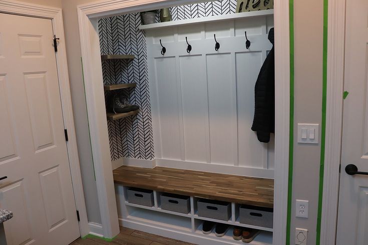 a mud room with white walls and wood flooring