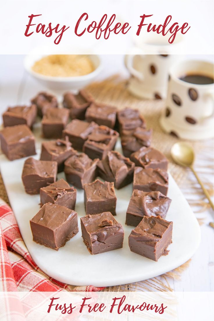 there are many pieces of chocolate on the plate and two cups of coffee in the background