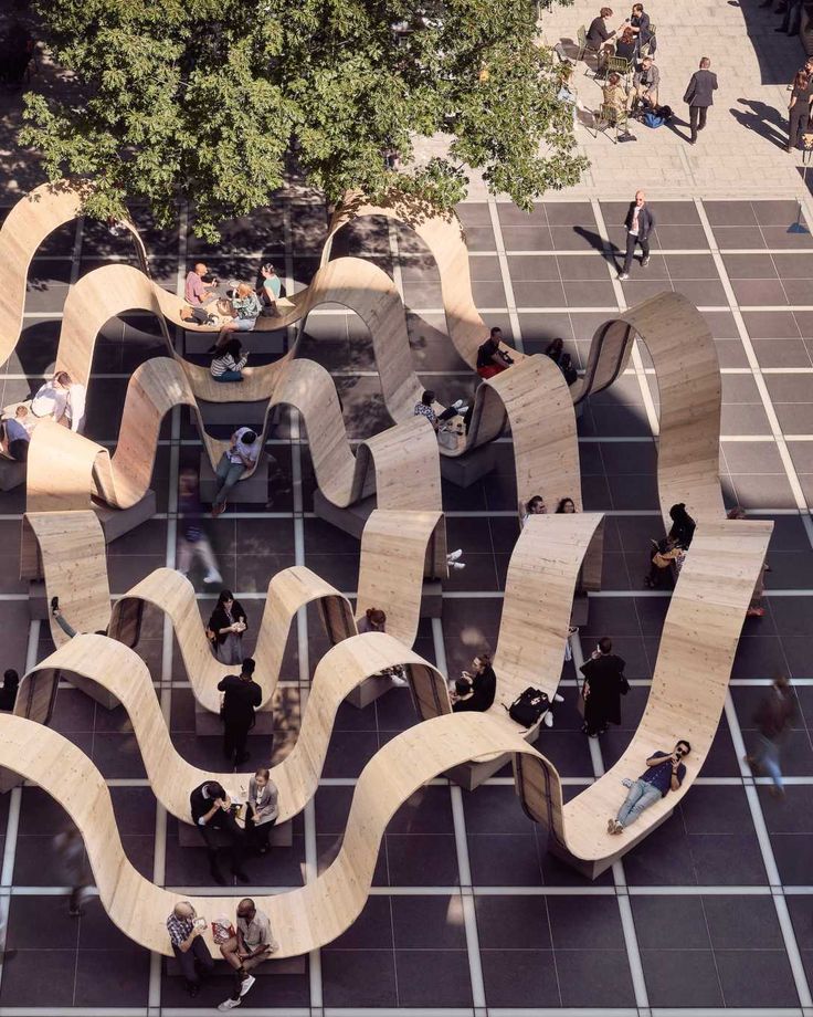 an aerial view of people walking and sitting on benches in the middle of a courtyard