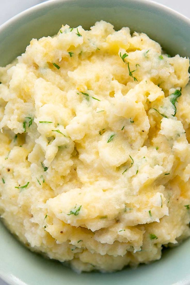 a bowl filled with mashed potatoes and garnished with green sprigs