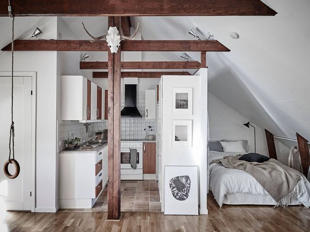 an attic bedroom with wood flooring and white walls, has exposed beams on the ceiling