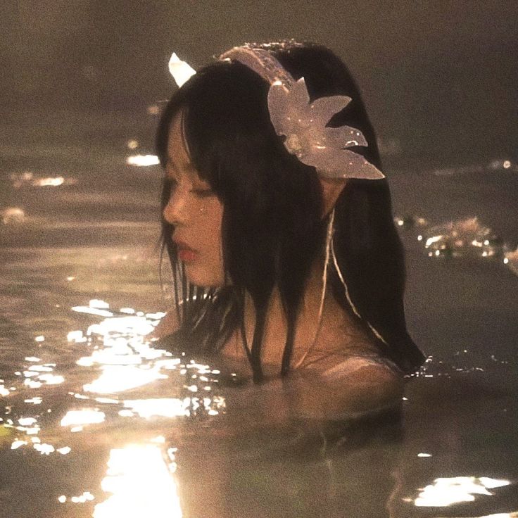 a woman is in the water with her headband on and hair combed back