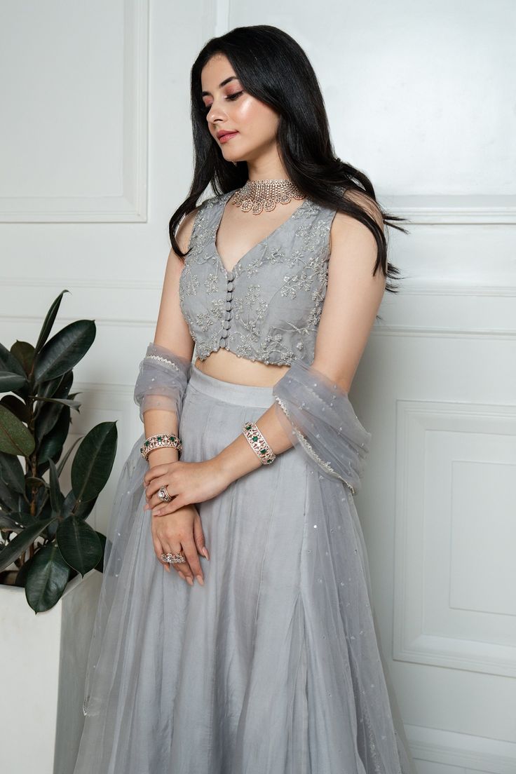 Grey lehenga in organza base with lace border on hem. Paired with floral hand embroidered blouse and net dupatta.
Component: 3
Pattern: Embroidered
Type Of Work: Sequin, Cutdhana, Bead
Neckline: V neck
Sleeve Type: Half
Fabric: Organza, Net
Color: Grey
Other Details: 
Hand embroidery
Back tassel tie-up
Front button detailing
Occasion: Wedding - Aza Fashions Grey Lehenga, Hand Embroidered Blouse, Embroidered Lehenga, Beaded Neckline, Net Dupatta, Lace Border, Embroidered Blouse, Set For Women, Aza Fashion