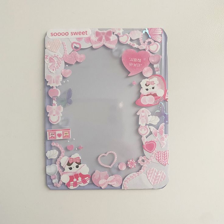 a pink and white photo frame with hello kitty stickers on the front, attached to a wall