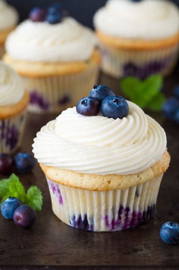 blueberry cupcakes with white frosting and fresh berries on the side, ready to be eaten