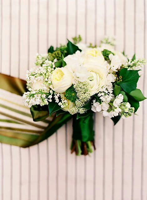 a bridal bouquet with white flowers and greenery on a striped wallpapered background