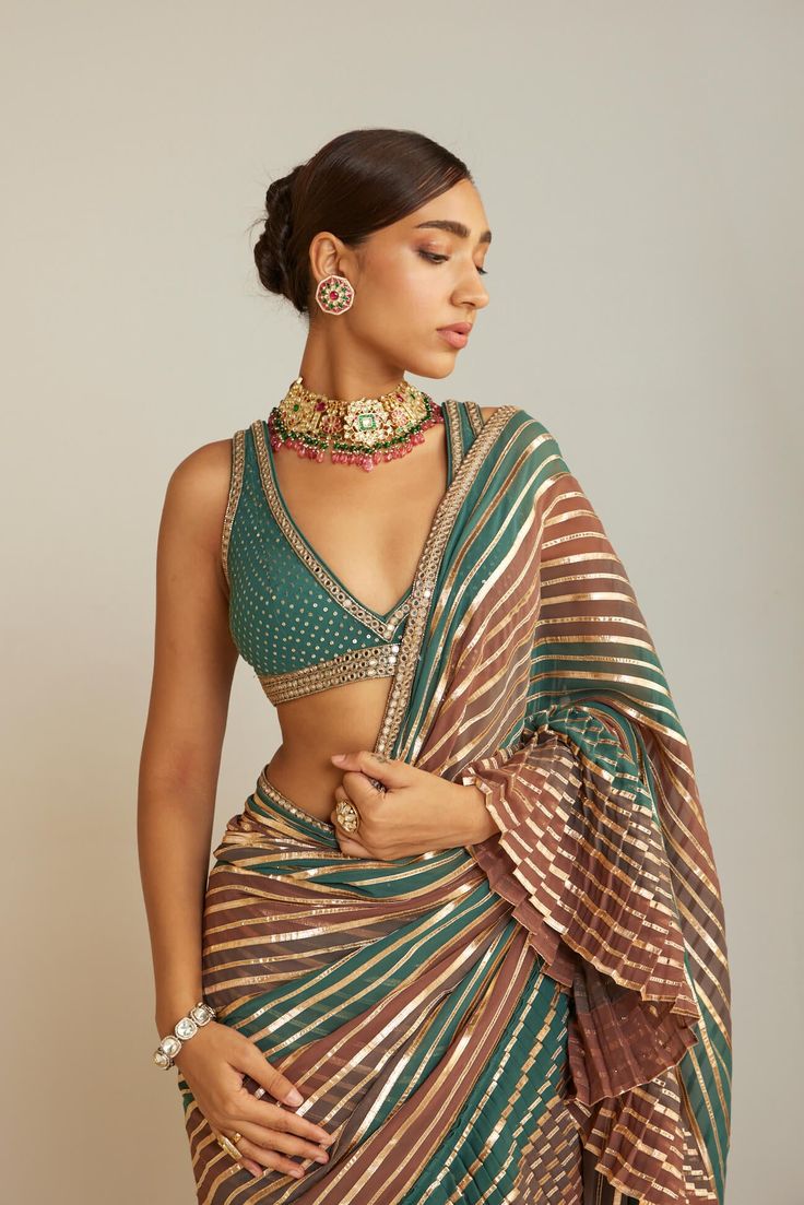 Editor's Note Indulge in sophistication with a hand-embroidered V-neck blouse, perfectly complemented by a radiant multicolor gota Sari. This ensemble harmoniously blends intricate artistry with vibrant modernity. Fabric: Georgette Color: Green Components: Sari and blouse Occasion: Festive Disclaimer: Product color may slightly vary due to photographic lighting sources or your monitor setting. Care: Dry clean only About the Designer Vvani by Vani Vats is a renowned Indian ethnic women's wear lab Luxury Motifs Blouse For Festivals, Luxury Blouse For Festivals, Luxury Raw Silk Blouse For Festivals, Luxury Elegant Blouse For Festivals, Luxury Unstitched Blouse Piece With Traditional Patterns, Luxury Designer Festive Blouse, Sarees Blouses For Women, Luxury Traditional Blouse With Traditional Patterns, Luxury Bollywood Blouse For Festive Occasions