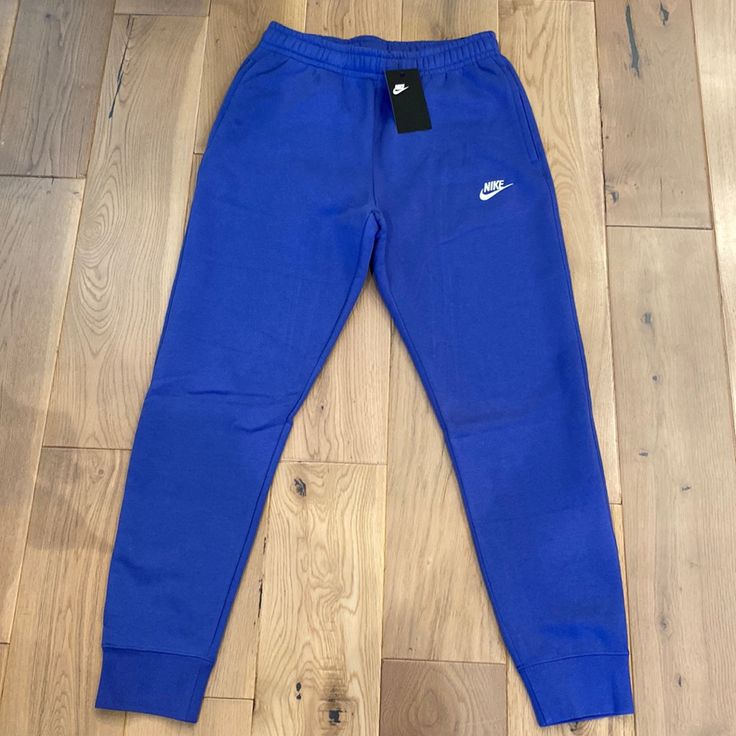 New With Tags Blue Cotton Sportswear Joggers, Nike Blue Relaxed Fit Sweatpants, Sporty Blue Cotton Pants, Nike Athleisure Tapered Leg Bottoms, Nike Tapered Leg Athleisure Bottoms, Blue Sweatpants With Elastic Waistband For Jogging, Casual Blue Nike Joggers, Blue Sports Pants With Tapered Leg, Sporty Blue Straight Leg Sweatpants