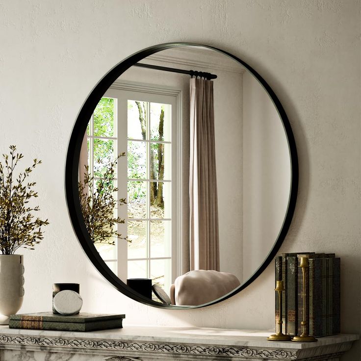 a round mirror sitting on top of a mantle next to a vase with flowers in it