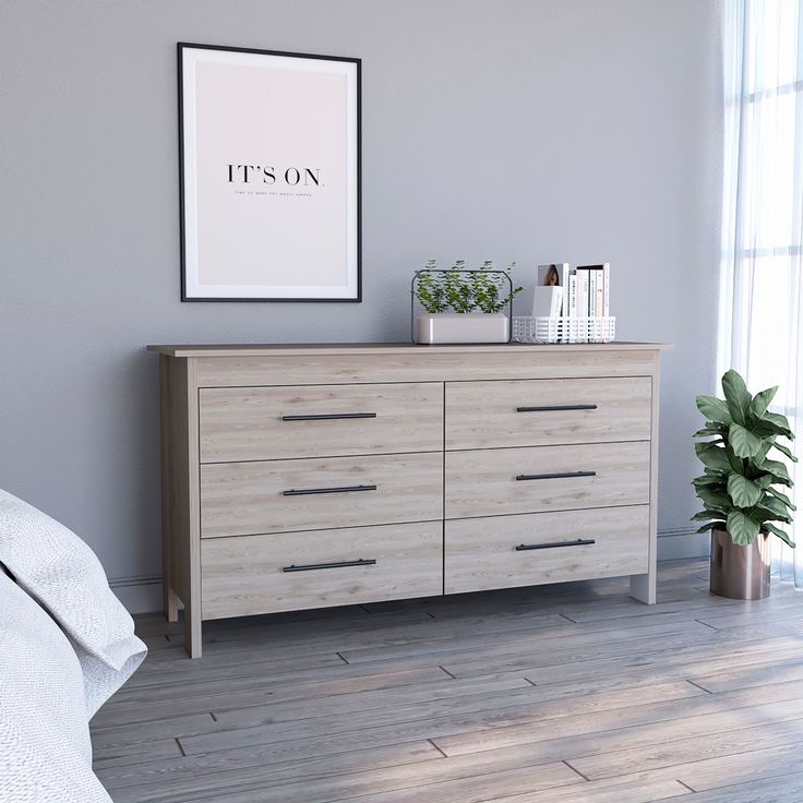 a bedroom scene with focus on the dresser and poster above it's headboard