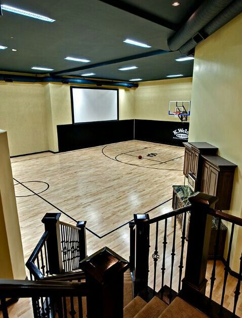 an indoor basketball court with stairs leading up to it