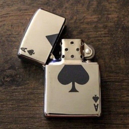 two lighters with playing cards on them sitting on top of a wooden table next to each other