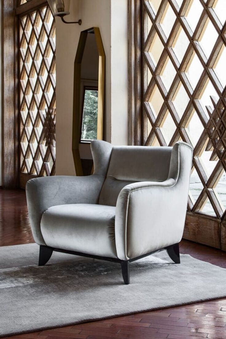 a chair sitting on top of a hard wood floor next to a wall mounted mirror