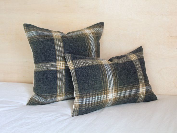 two black and white plaid pillows sitting on top of a bed next to each other