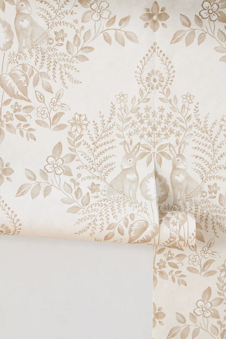 the wall paper is white and has gold flowers on it, along with two matching sheets