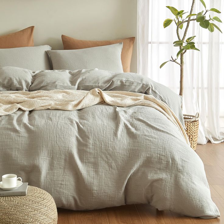 a bed with pillows and blankets on top of it next to a potted plant