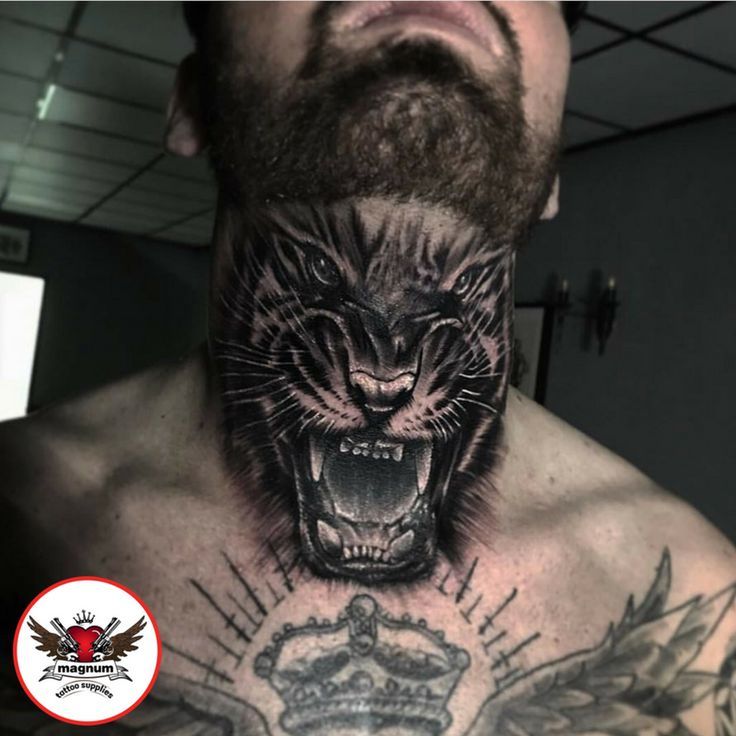 a man's chest with a tiger and crown tattoo on his neck, in front of a mirror