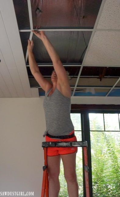 a woman standing on a ladder working on the ceiling