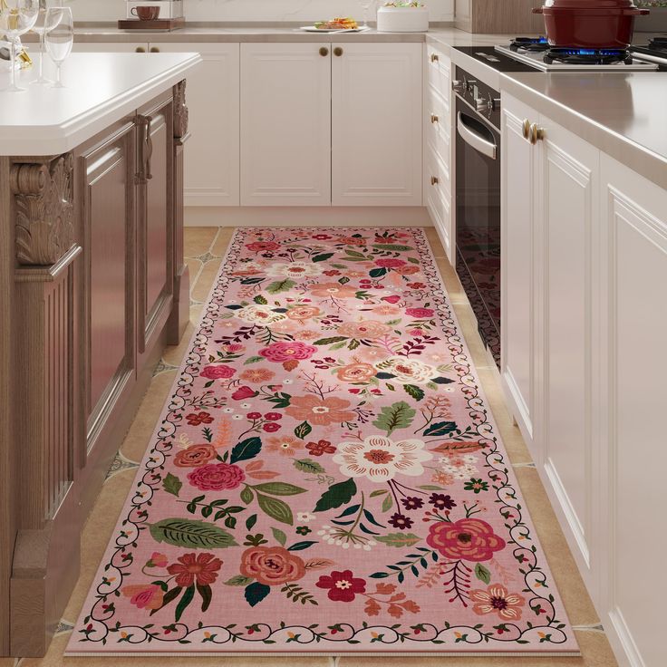 a kitchen with white cabinets and pink floral rug on the floor next to an oven