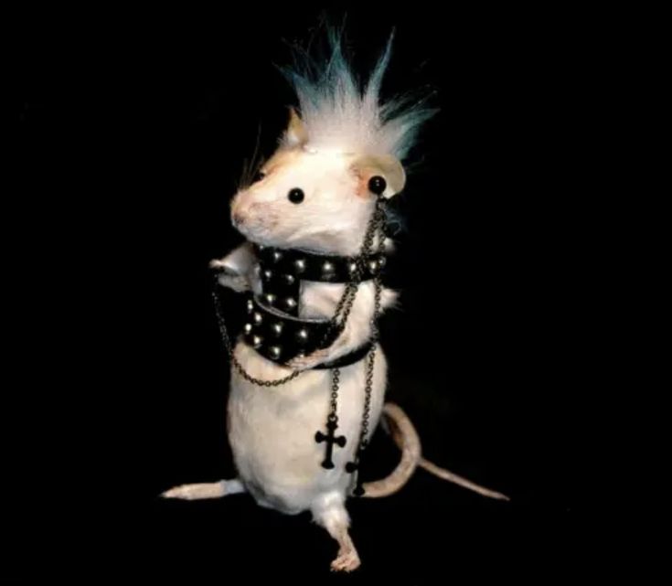 a white rat with blue hair and chains on it's back, standing in the dark